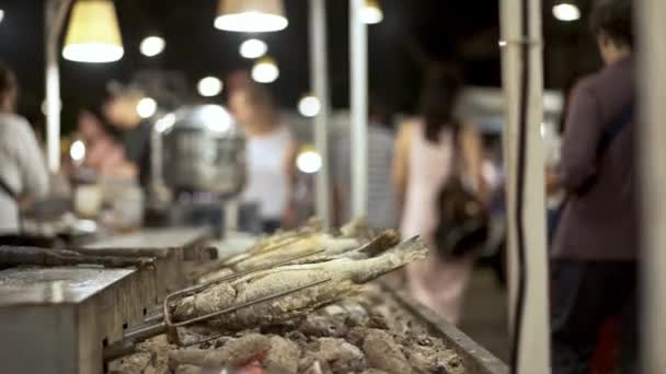 Handheld tiro de peixe sendo frito em espetos, mercado de comida tailandesa de rua — Vídeo de Stock