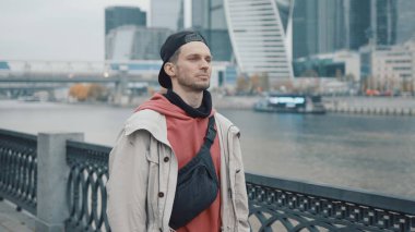 Kırmızı kapüşonlu bir adam iş dünyasının arka planında yürüyor.