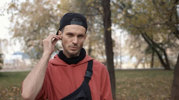 Hombre corredor poner en auriculares y toque en smartwatch en el parque de la ciudad prepararse para correr. Retrato plano — Foto de Stock