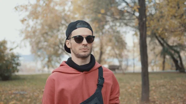 Hombre corredor en gafas puestas en auriculares en el parque de la ciudad prepárate para correr — Foto de Stock