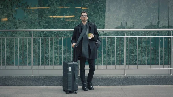 Homem de casaco preto com mala esperar por um táxi no fundo do terminal do aeroporto — Fotografia de Stock