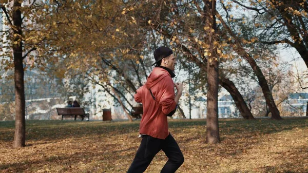 Hombre corredor en ropa deportiva en el parque de otoño en la ciudad, cámara lenta — Foto de Stock