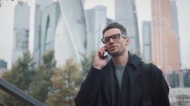 Paltolu bir adam telefonda konuşuyor sonbahar günü gökdelenlerin arka planında