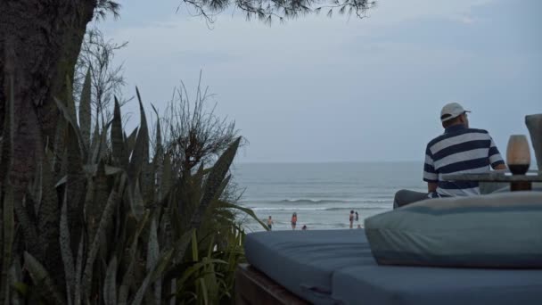 TAILANDIA, HUA HIN - 12 DE ENERO DE 2020: Gimbal de personas sentadas en la playa de Hua Hin mirando al horizonte — Vídeos de Stock