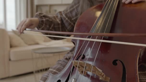 Jovem músico com arco nas mãos tocando violoncelo em casa — Vídeo de Stock