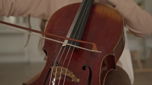 Jonge vrouw muzikant met strik in de handen cello spelen thuis — Stockvideo