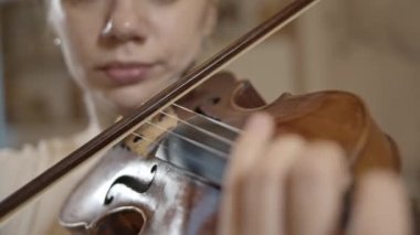 Kadın profesyonel müzisyen keman çalıyor. Yakın plan, bulanık arka plan.