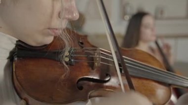 Kadın kemancı, iç mekanında çello eşliğinde yakın plan çalıyor.