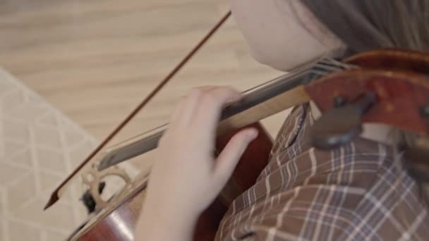 Νεαρή γυναίκα μουσικός με τόξο στα χέρια παίζοντας τσέλο στο εσωτερικό του σπιτιού — Αρχείο Βίντεο