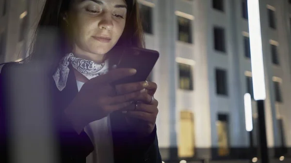 Vrouw close-up met een telefoon dragen zwarte jas en nek sjaal, nacht schot — Stockfoto