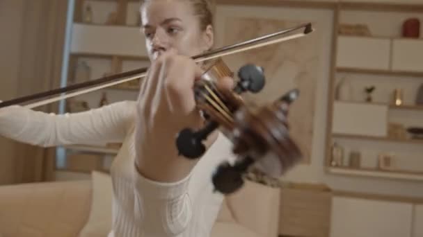 Fiatal szőke nő játszik hegedű közelkép, minimalista otthoni belső — Stock videók