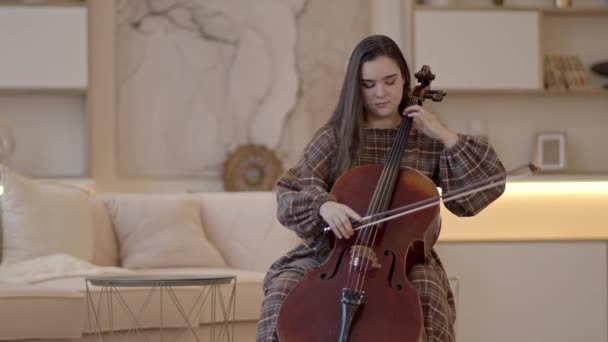 Jonge vrouw lang haar spelen cello zitten in luxe interieur — Stockvideo