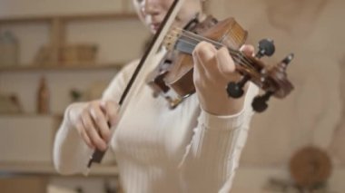 Genç sarışın kadın keman çalıyor. Yakın plan, minimalist ev dekorasyonu.