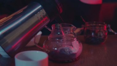Barda çay seremonisi, neon ışıklarda cam çaydanlığa sıcak su dökmek.