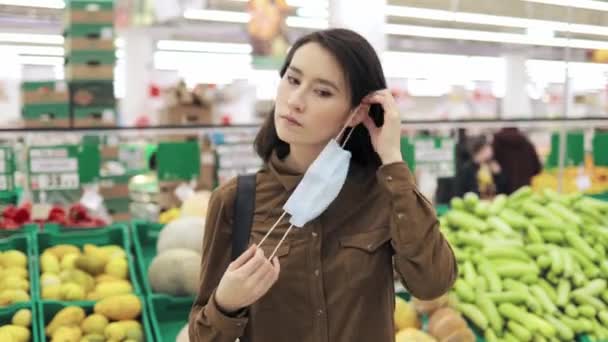 Jovem mulher colocando máscara protetora no supermercado — Vídeo de Stock