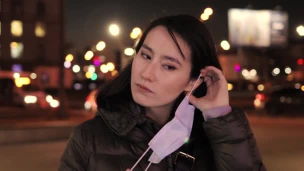 若い女性は夜の街の保護マスクにライトをつけて — ストック動画