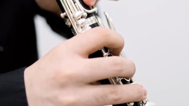 Мужские пальцы играют на кларнете на белом фоне, мужчина в черной одежде — стоковое видео
