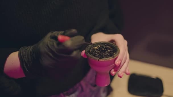 Handen in het zwart handschoenen maken van een kom voor hookah, bar neon lichten — Stockvideo