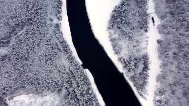 İnsansız hava aracı kar ormanları ve nehirlerin üzerinden uçuyor, ağaçların tepeleri karla kaplı.