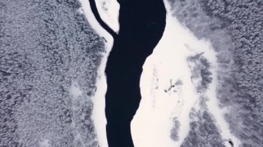 İnsansız hava aracı kar ormanları ve nehirlerin üzerinden uçuyor, ağaçların tepeleri karla kaplı. 