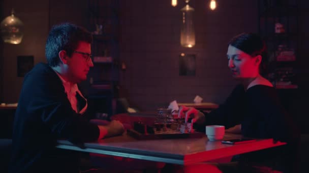 Чоловік і жінка грають в шахи п'ють чай в барі в приміщенні — стокове відео