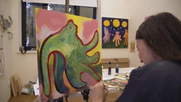 Женщина-художник с мольбертом держит кисть в студии современного искусства — стоковое видео