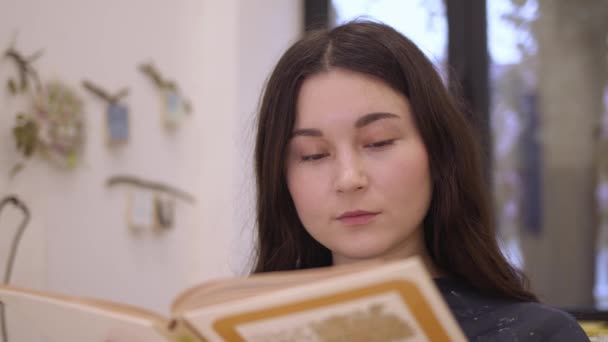 Ung kvinna närbild läsa bok i ljus studio inomhus — Stockvideo
