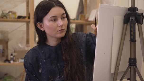 Fiatal nő festő festőállvánnyal dolgozik a modern művészeti stúdióban — Stock videók