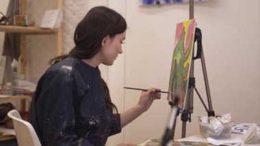 Parlak ışık resim stüdyosunda resim fırçası tutan kadın sanatçı.