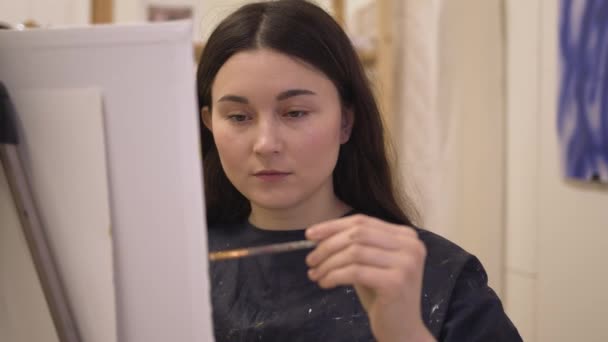 Jeune femme peintre avec chevalet travaillant dans un atelier d'art moderne — Video