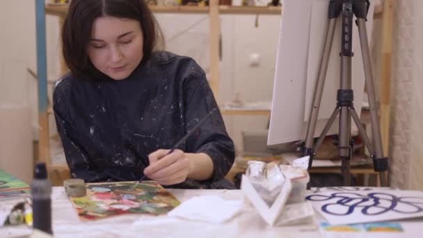 밝은 조명 예술 스튜디오에서 붓을 사용하여 그림을 그리는 여성 미술가 — 비디오