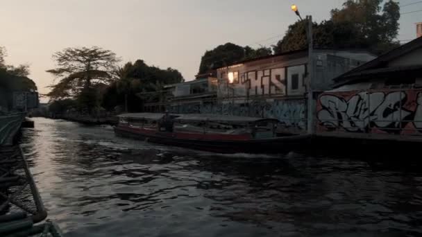 BANGKOK - JANUARI 16: Van links naar rechts pan real time vast te stellen schot van een boot langs het kanaal genomen van de oever. Verkeer op de rivieren van Bangkok, Thailand. — Stockvideo
