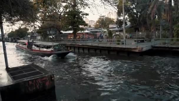 BANGKOK - JANUARI 16: Van links naar rechts pan real time shot van een boot die langs het kanaal van de oever. Verkeer op de rivieren van Bangkok, 16 januari, Bangkok, Thailand. — Stockvideo