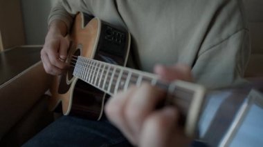 Evde hafif akustik gitar çalan bir müzisyen.