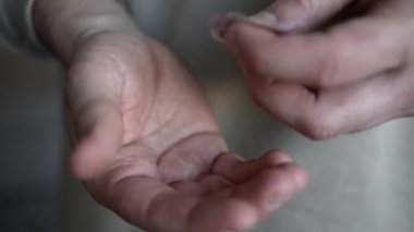 Elleri su toplamış, hapları çıkaran bir adam.