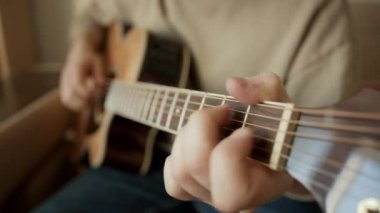 Evde hafif akustik gitar çalan bir müzisyen.