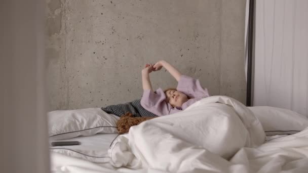 Ung kvinna vaknar upp på sängen med hund och kolla sin telefon för meddelanden — Stockvideo