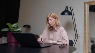 Tablet kullanan kadın grafik tasarımcısı, ofis odasında dizüstü bilgisayarla çalışıyor