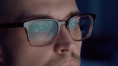 Geceleri borsa grafiklerini analiz eden bıyıklı ve gözlüklü bir tüccar.