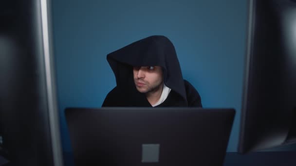 Man hacker in black hood working with several computers — Stock Video