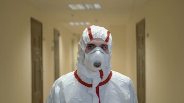 Лікар у захисному костюмі та масці, що йде в лікарняному коридорі, повільний рух — стокове відео