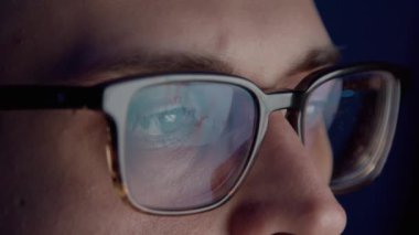 Gözlüklü adam geceleri bilgisayar ekranına bakıyor.