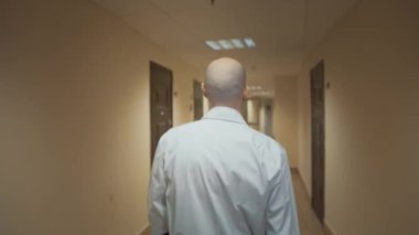 Beyaz önlüklü doktor hastanenin koridorunda yürüyor.