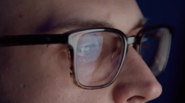 Gözlüklü adam geceleri borsa grafiklerini analiz ediyor.