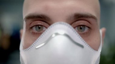 Hastanenin bulanık arka planında, ppe maske takmış erkek doktorun yakın çekimi.
