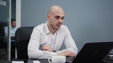 İş adamı, ofisteki bir video odasında kahve fincanıyla konuşuyor.