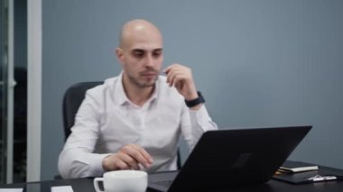 Ofis çalışanı bir sandalyeyle masaya geliyor, iş adamı dizüstü bilgisayarlı.