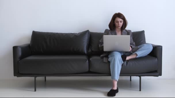 Üzletasszony dolgozik, ül a fekete kanapén a nappaliban otthon — Stock videók