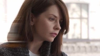 Sıcak kazaklı esmer kadın pencerenin yanında oturuyor çalışıyor, yakın plan çekiyor.