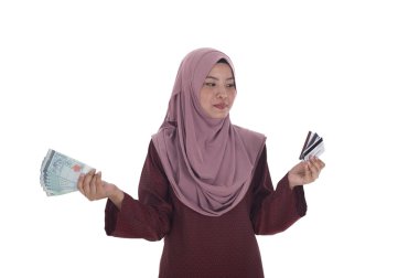 Malezya ringgiti bir sürü tutan gülümseyen bir Müslüman kadın ve 